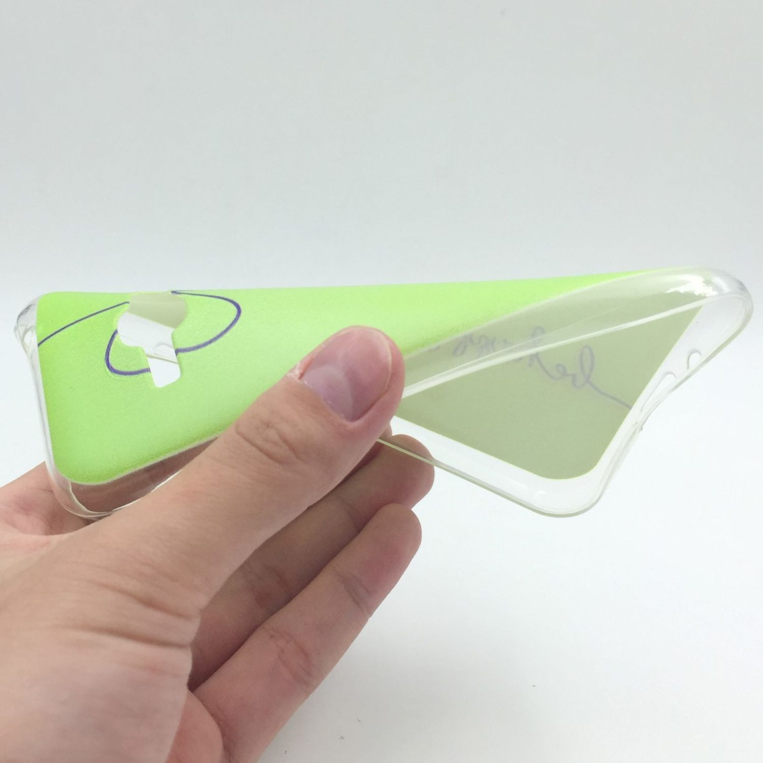 Hand hält eine transparente Handyhülle mit grünem Farbverlauf. Der Hintergrund ist weiß.