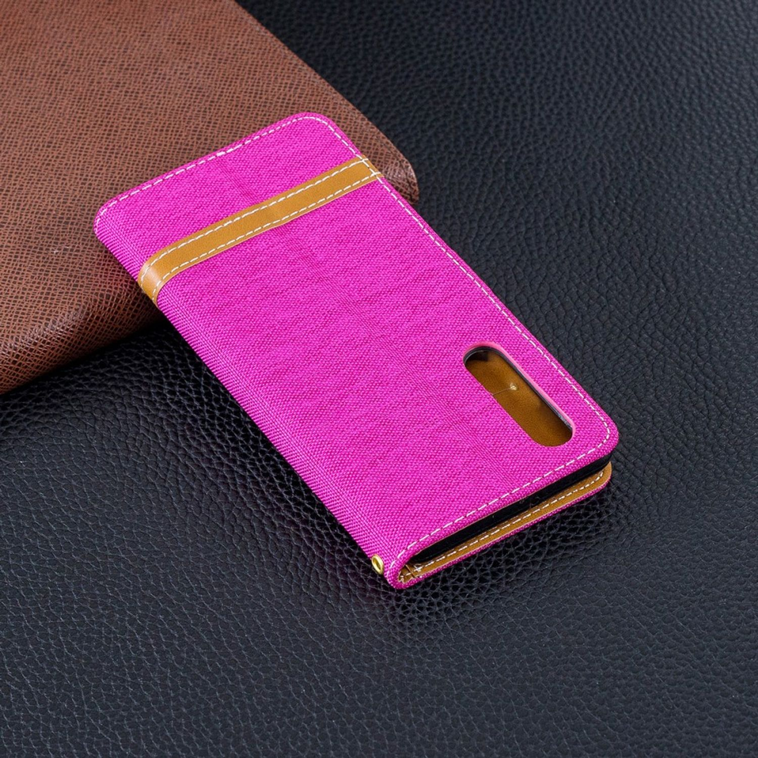 Rosa Handyhülle mit braunem Rand und einem Schlitz für ein Telefon auf dunkler Oberfläche.