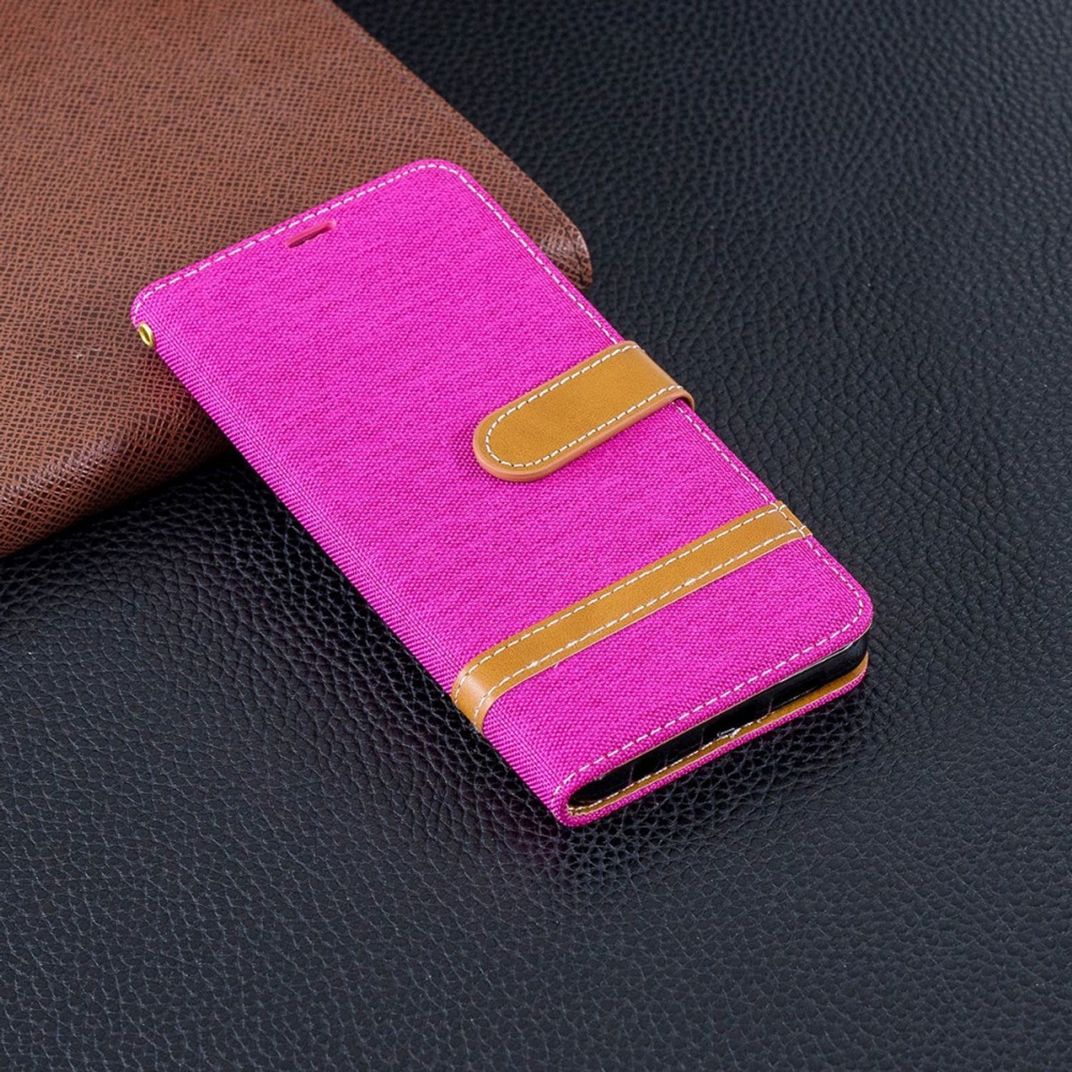 Rosa Handyhülle mit braunem Riemen und Hintergrund. Schwarzer Tisch.