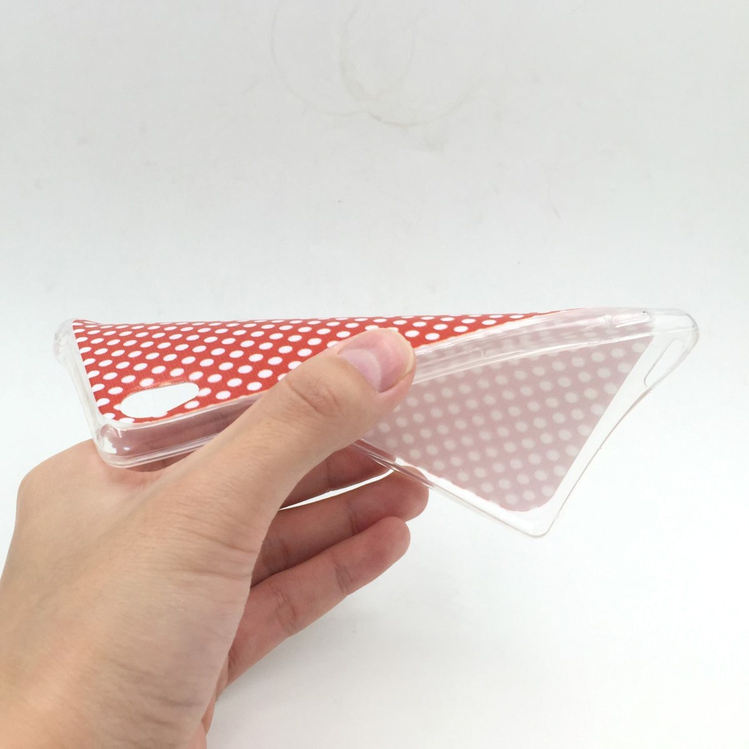 Hand hält eine rote Handyhülle mit Tupfen.