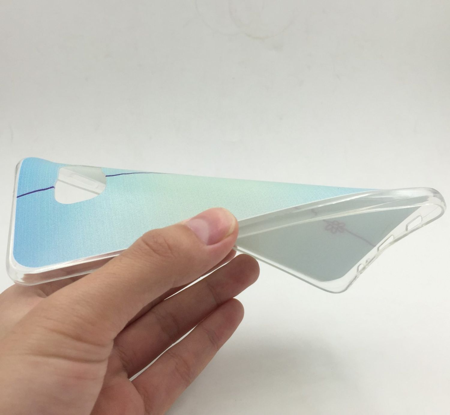 Eine Hand hält eine transparente Handyhülle mit einem blauen Farbverlauf. Die Hülle ist biegsam.