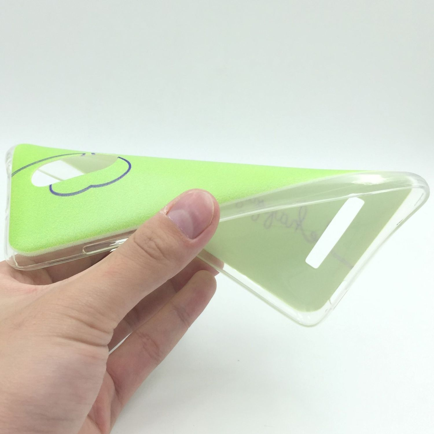 Hand hält eine grüne Handyhülle. Die Hülle ist durchsichtig und hat ein Design. Weißer Hintergrund.