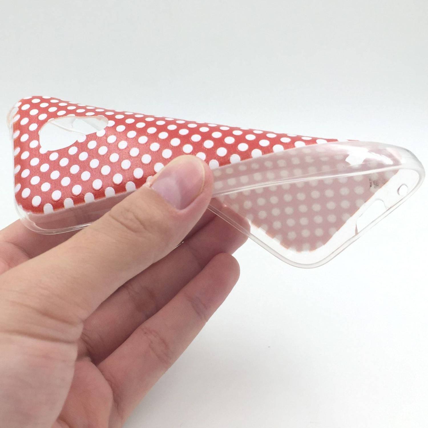 Hand hält transparente Handyhülle mit roten Punkten. Weißer Hintergrund.