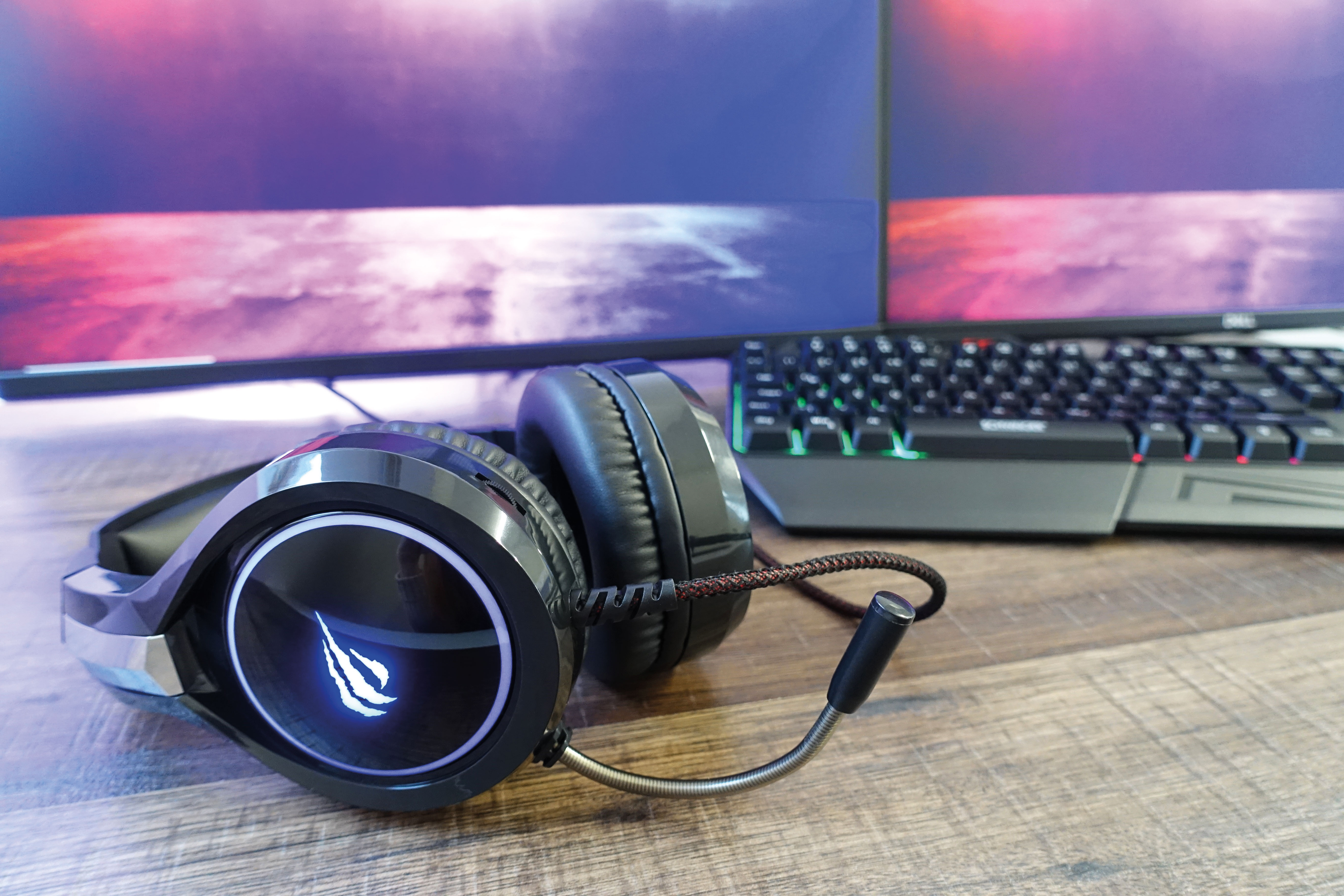 Gaming-Headset mit Mikrofon, schwarz und silber, auf einem Holztisch.