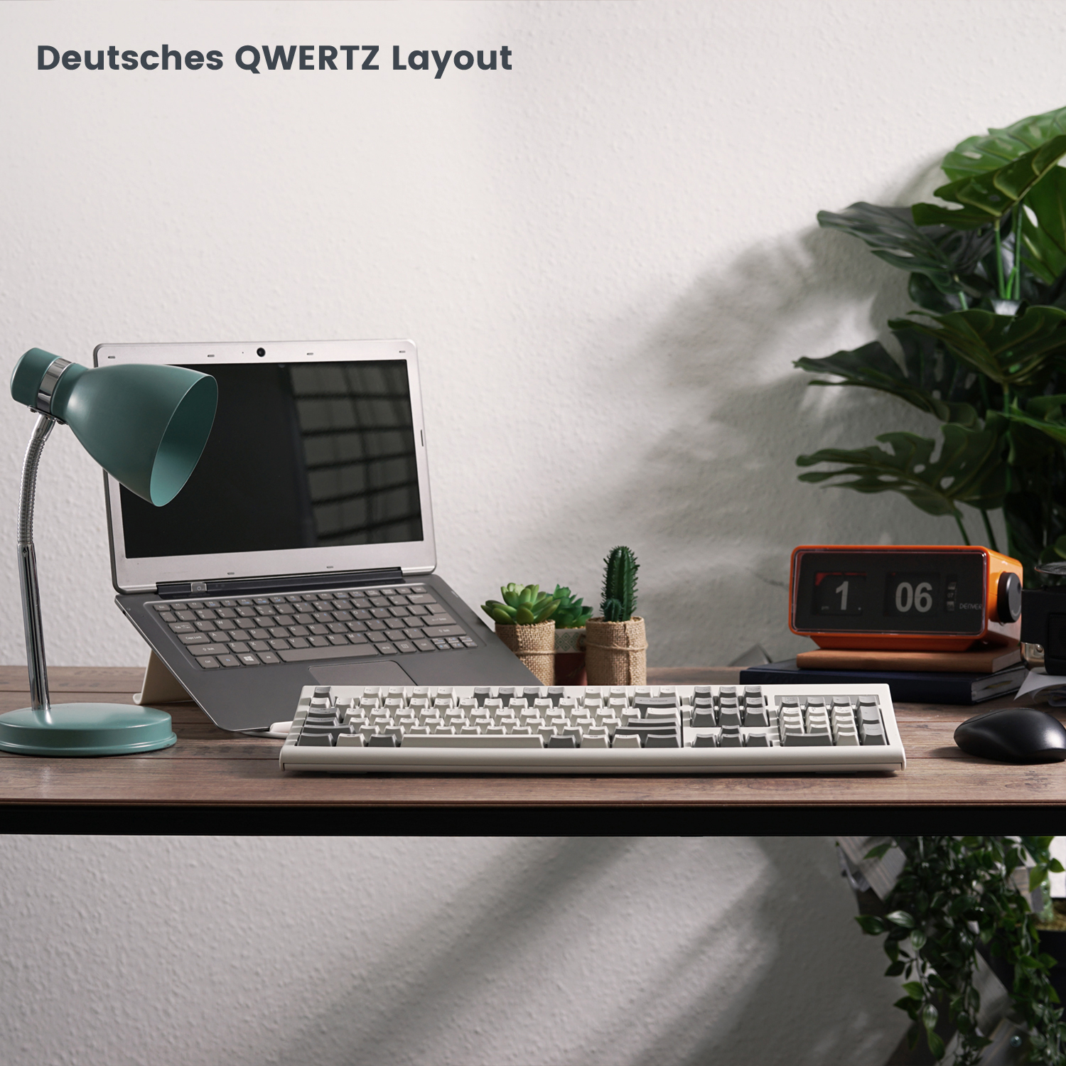Ein Schreibtisch mit Laptop, mechanischer Tastatur und Lampe. Oben steht: Deutsches QWERTZ Layout.