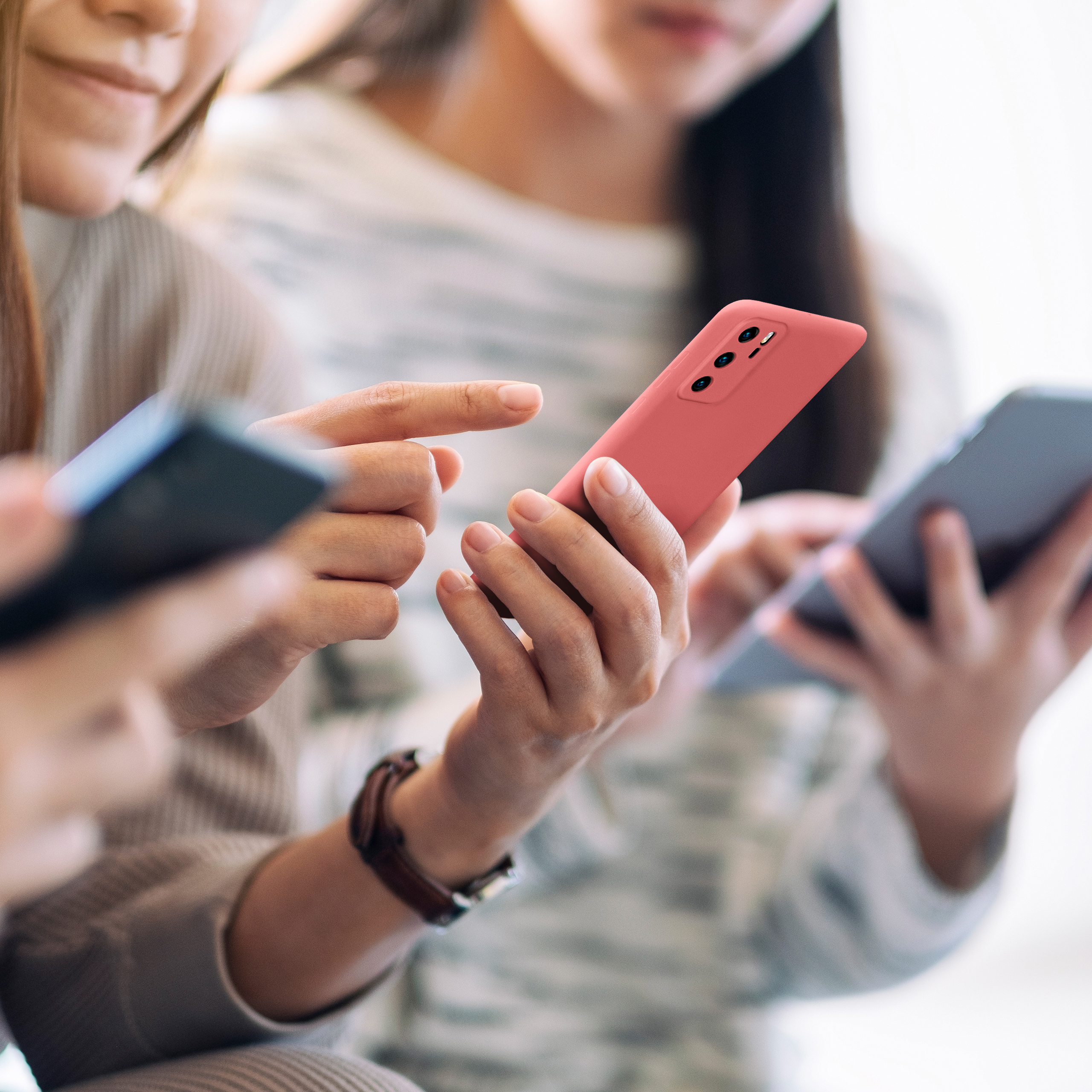Personen halten Smartphones. Eine rote Hülle ist im Fokus.