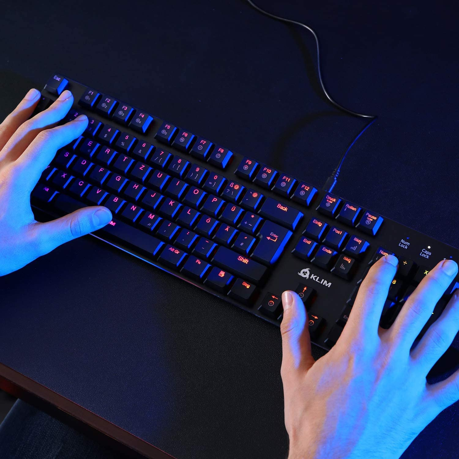 Hände tippen auf einer schwarzen Tastatur mit blau und rot beleuchteten Tasten.