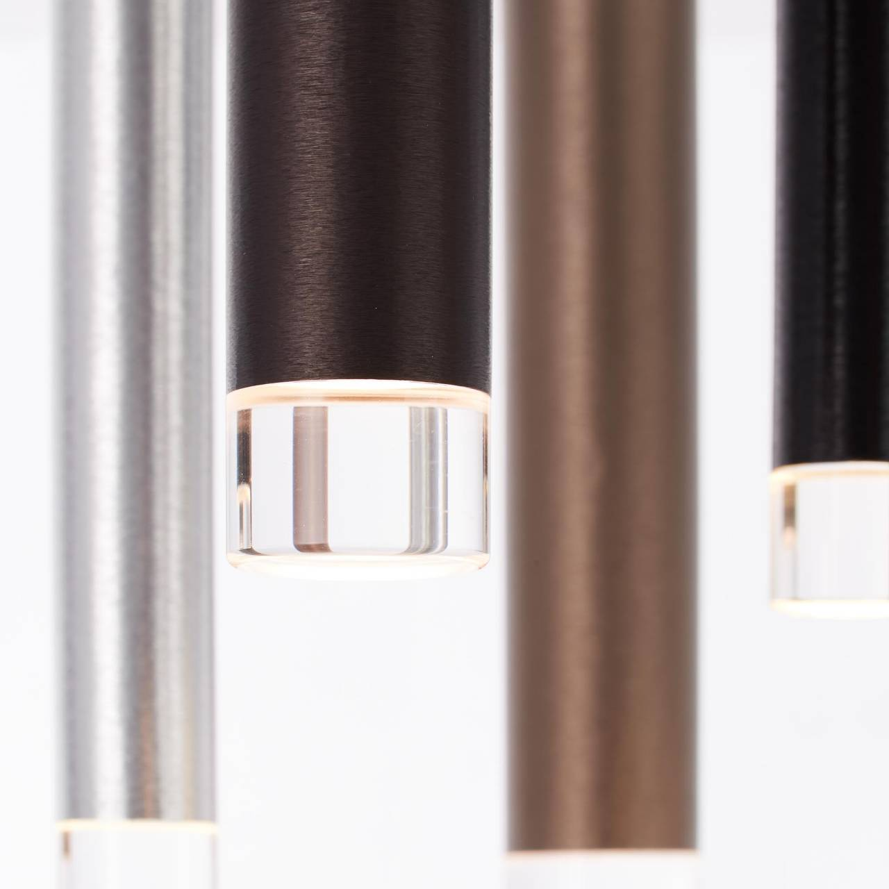 Nahaufnahme von hängenden zylindrischen Lichtern in Silber, Braun und Schwarz.