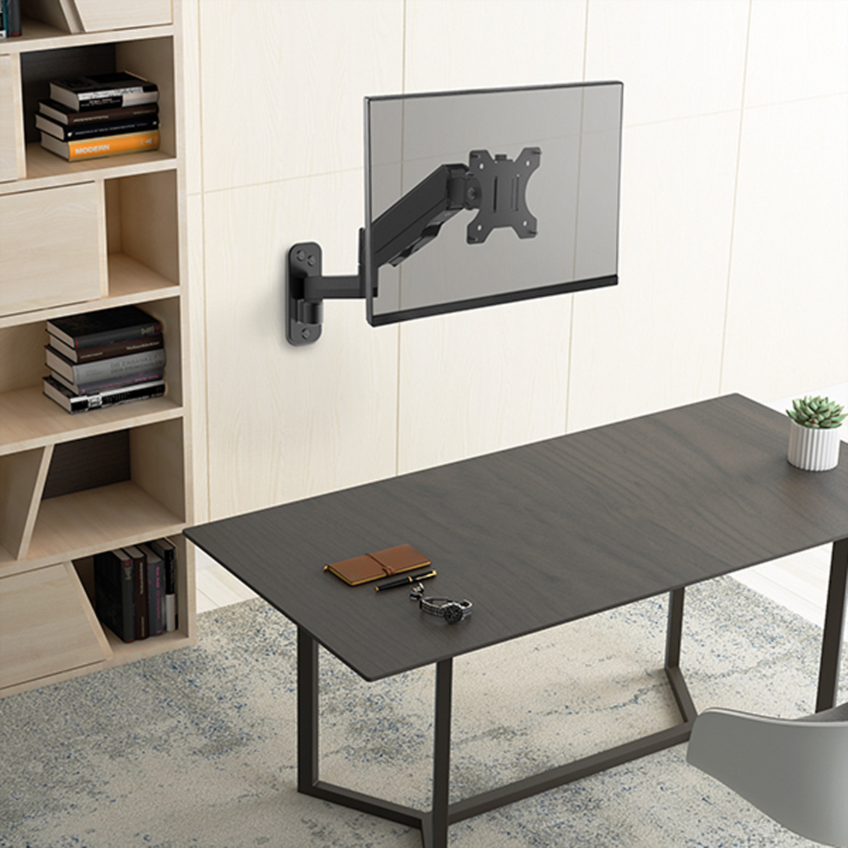 Ein Monitor an einer Wand montiert, mit Arm. Schreibtisch darunter mit Büchern und Pflanze.