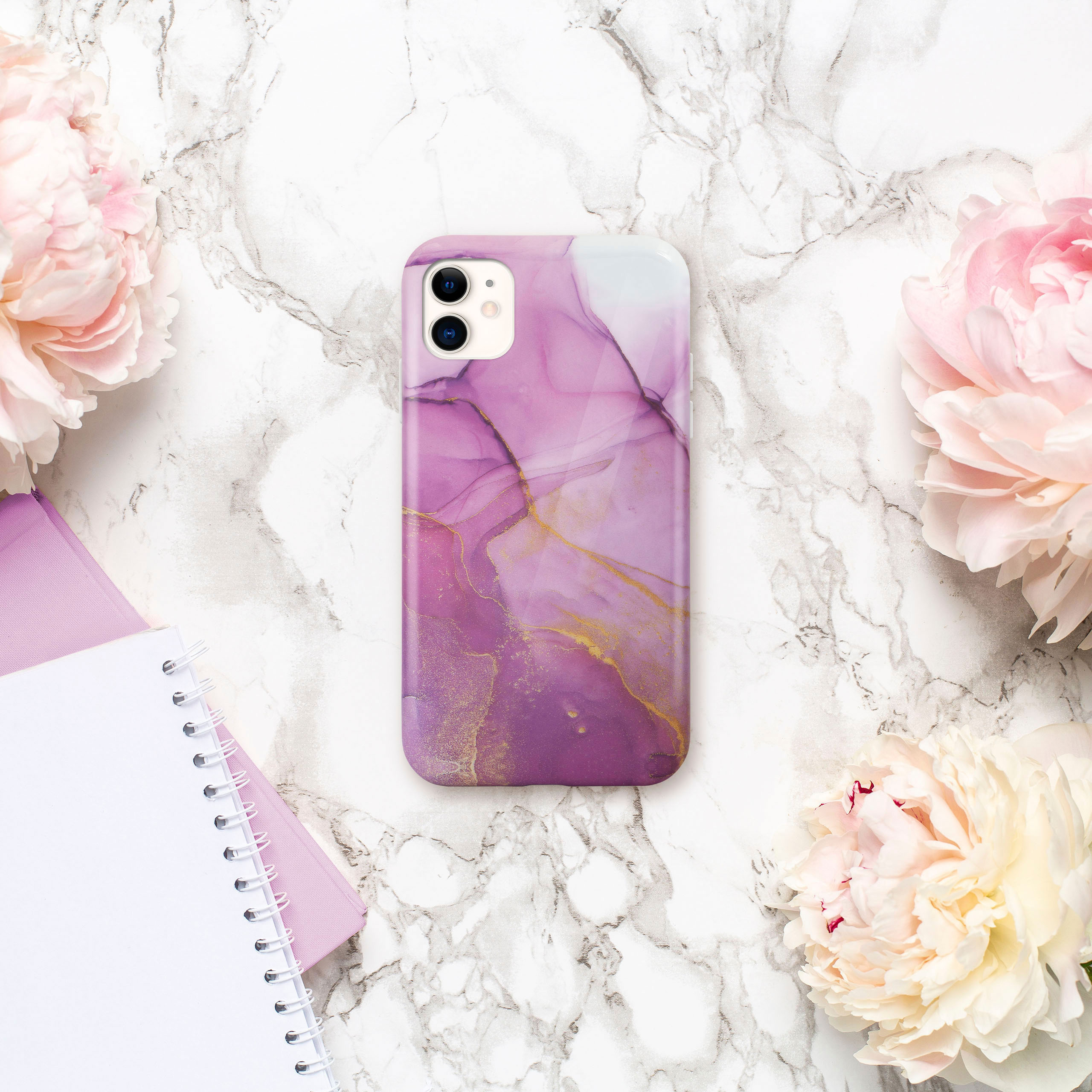 Handyhülle mit lila und goldenem Marmor-Design, Blumen und Notizbuch.