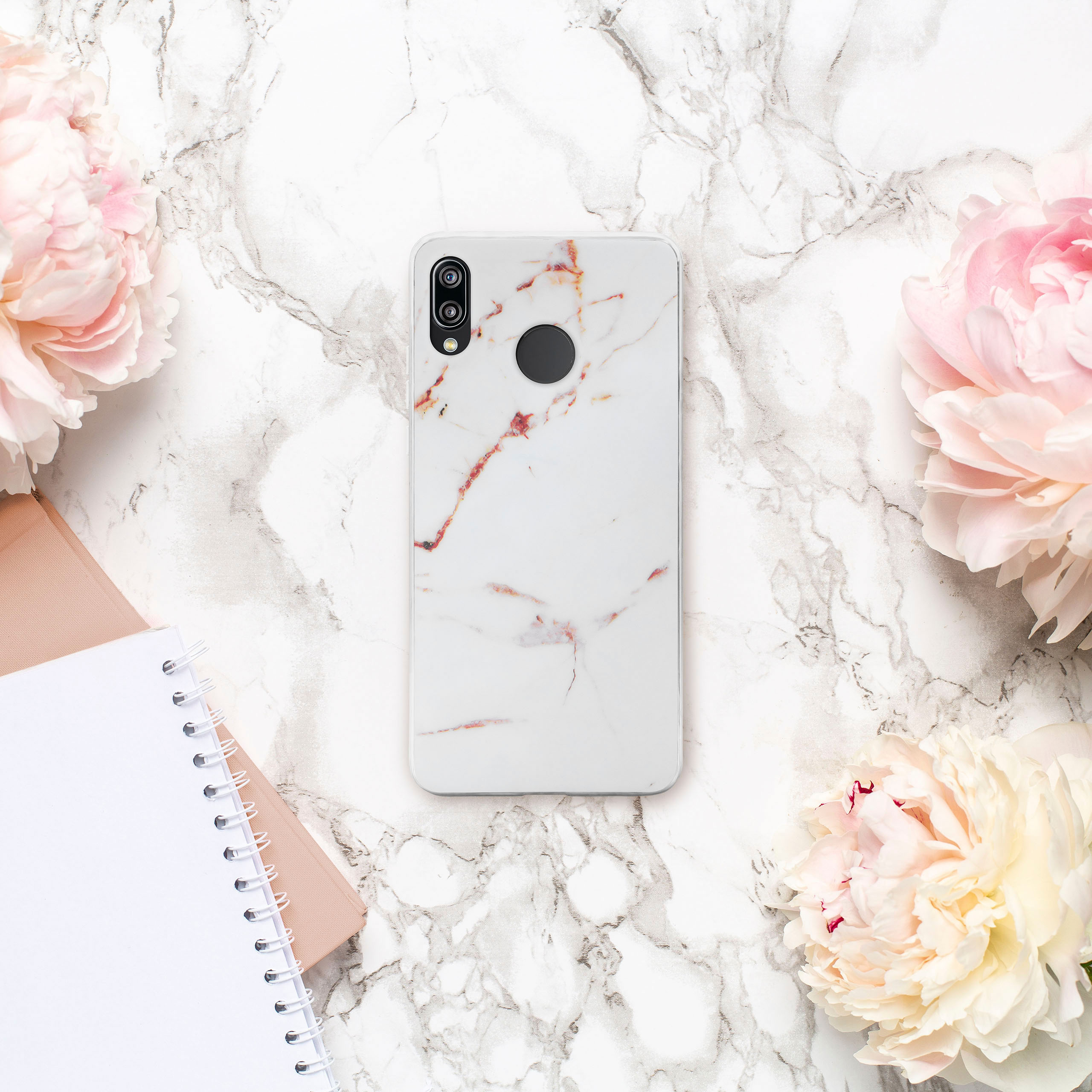 Handyhülle mit Marmordesign, umgeben von Blumen und einem Notizbuch.
