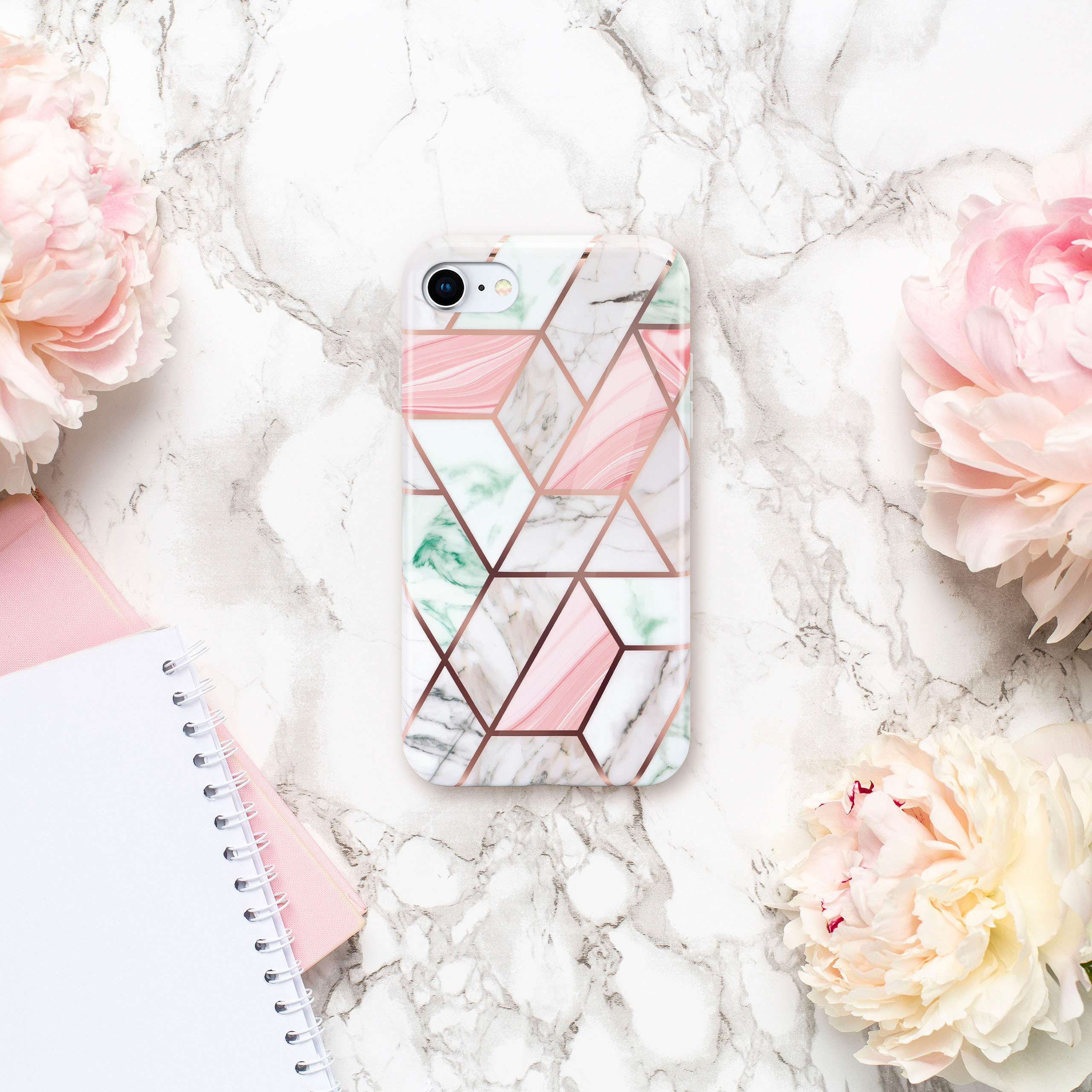 Handyhülle mit geometrischem Design. Rosa Pfingstrosen und Notizbücher auf Marmoroberfläche.