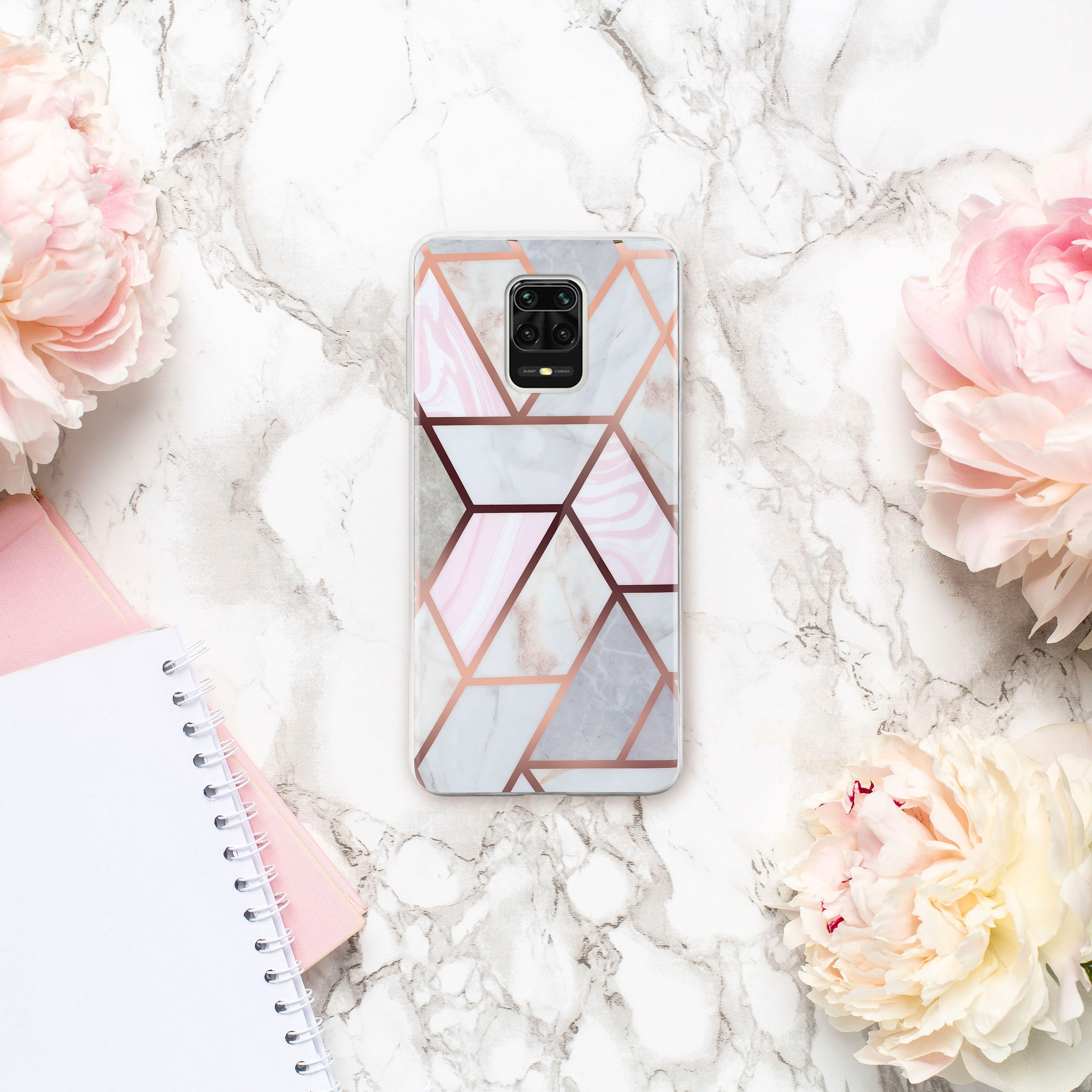 Handyhülle auf Marmor mit Blumen, geometrischem Design, rosa und goldfarben. Notizbücher sind ebenfalls sichtbar.