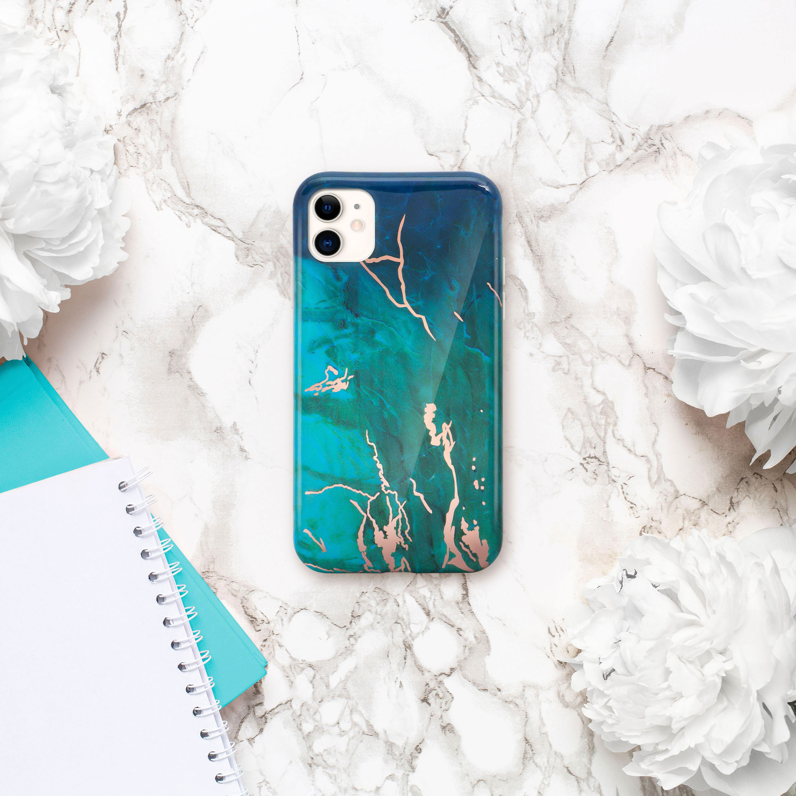 Handyhülle mit blau-grünem Marmordesign, Goldakzenten, umgeben von Blumen und Notizblöcken.