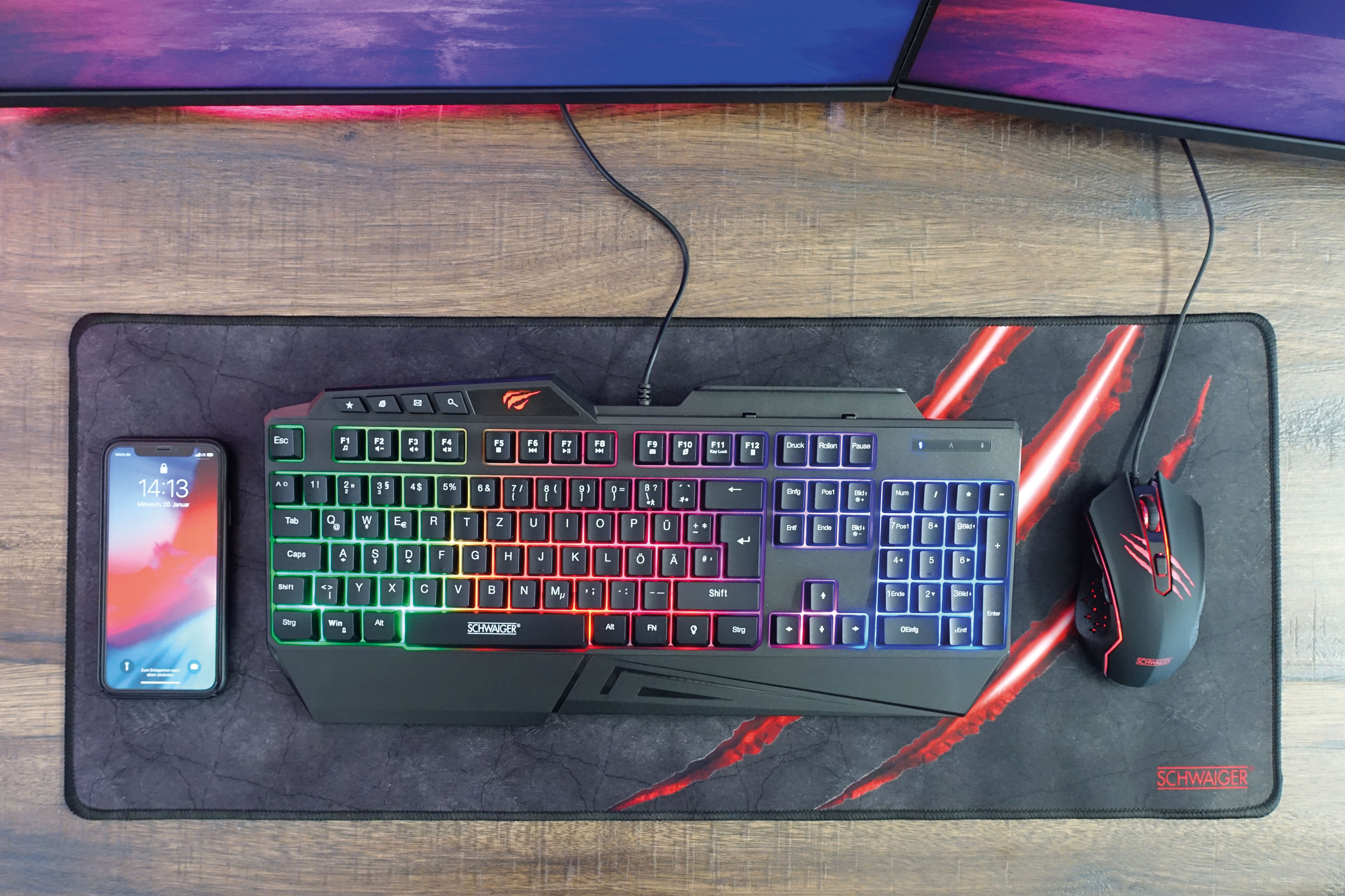 Eine Gaming-Tastatur, Maus und Telefon befinden sich auf einem Gaming-Mauspad mit roten Details.