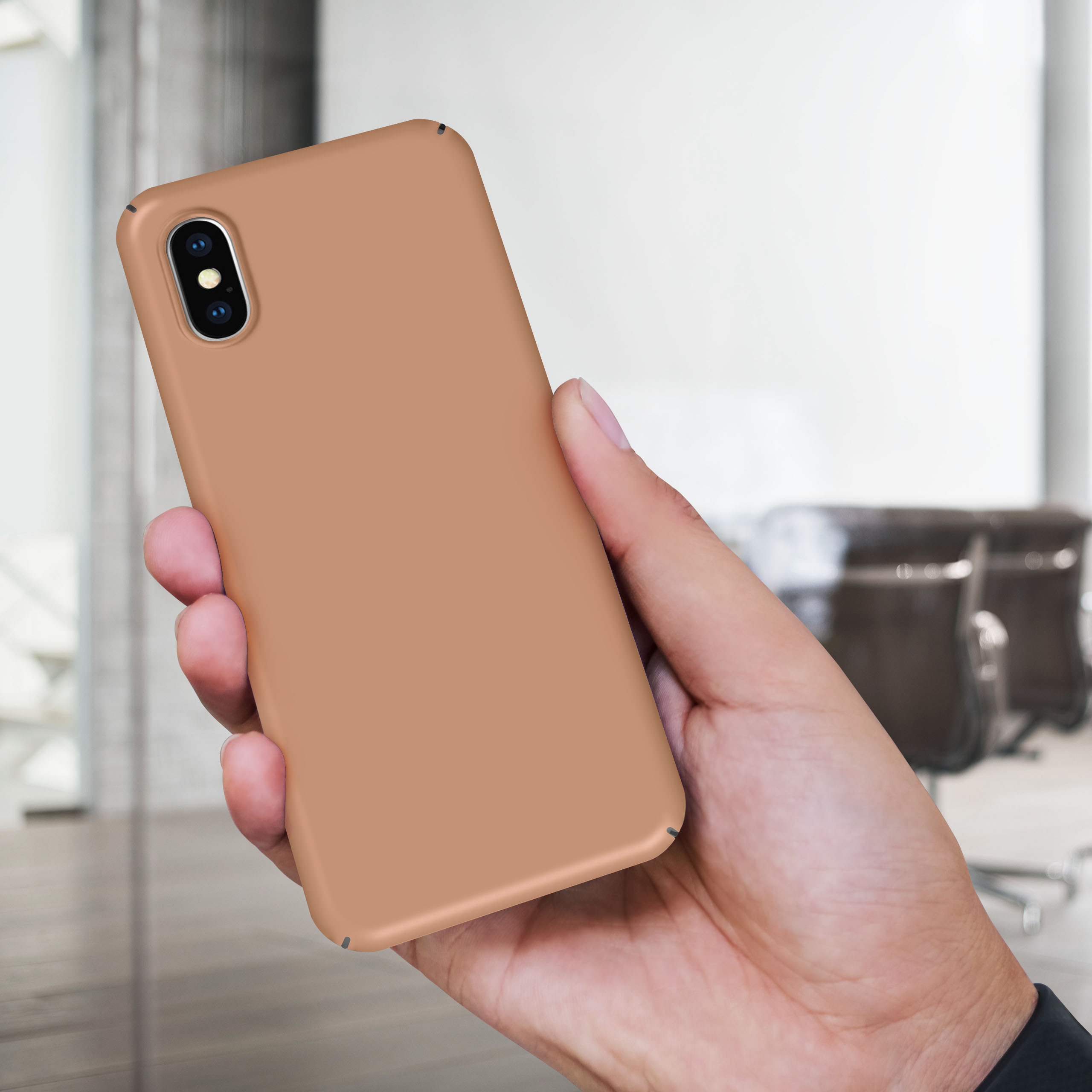 Hand hält ein beigefarbenes Telefon mit Hülle. Verschwommener Bürohintergrund.