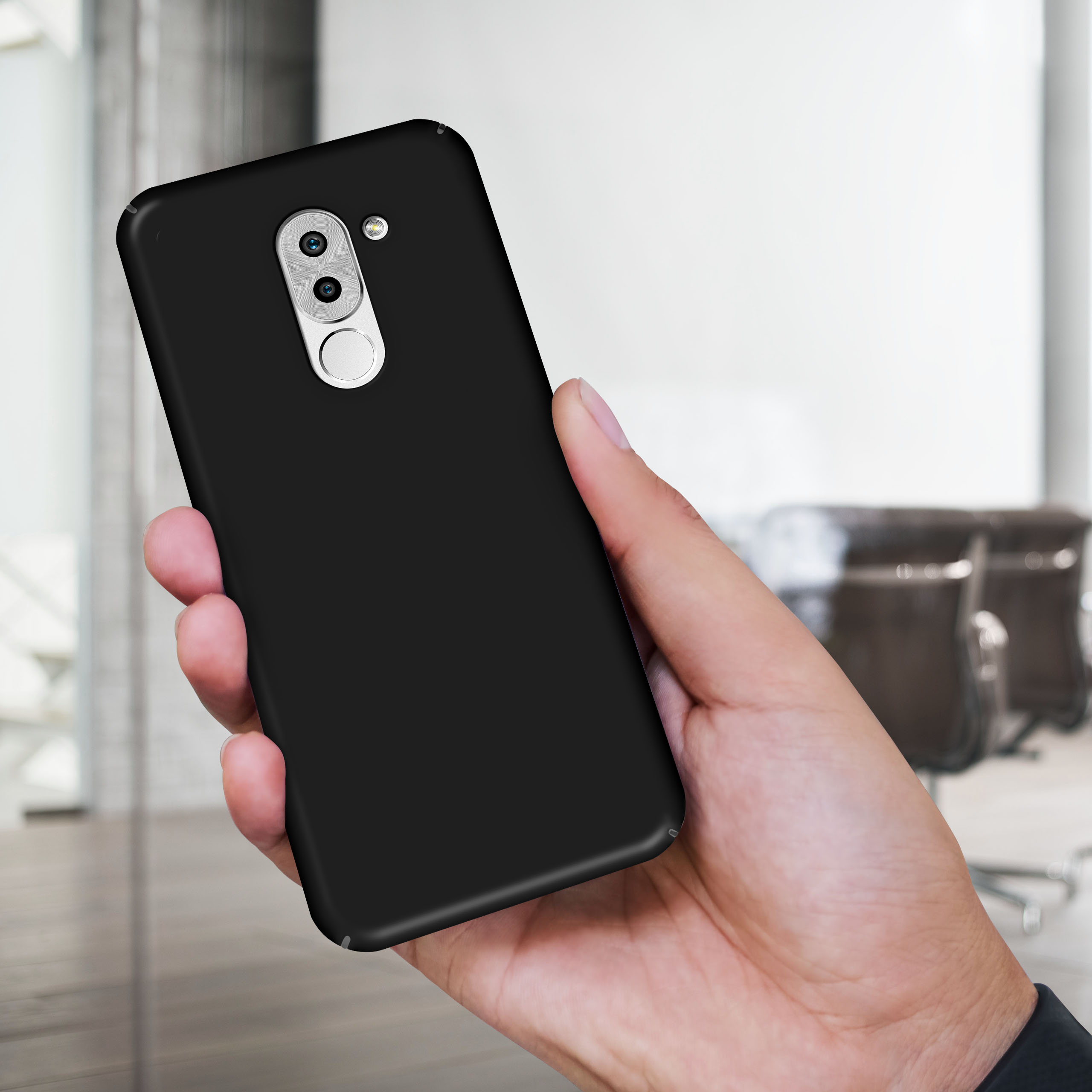 Eine Hand hält ein schwarzes Telefon mit schwarzer Hülle.