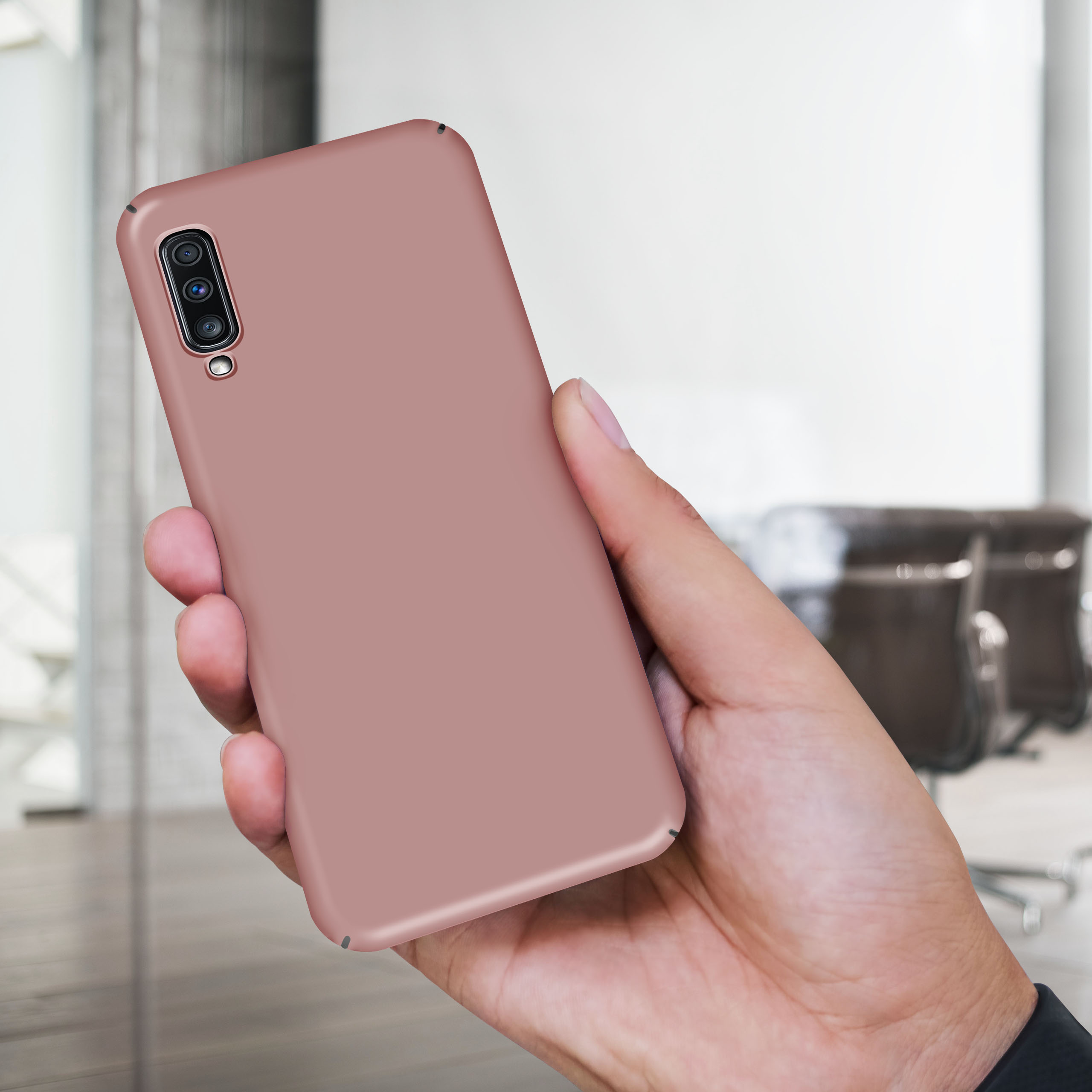 Eine Person hält eine rosa Handyhülle. Die Hülle befindet sich auf einem Telefon.