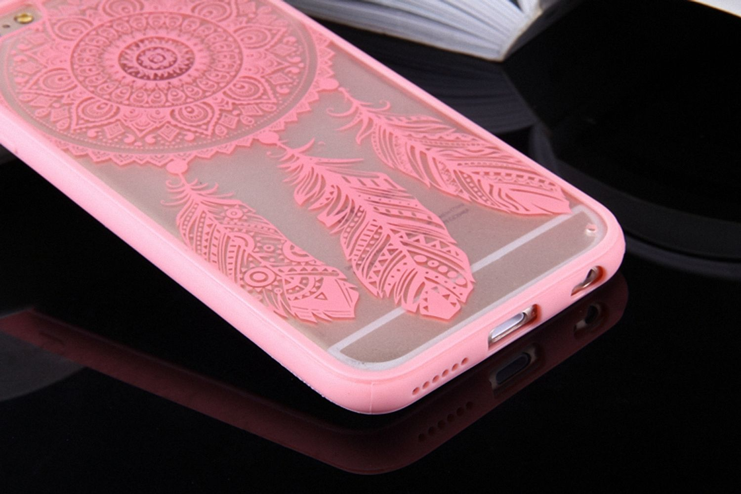 Eine rosa Handyhülle mit Mandala- und Federdesign. Das Telefon befindet sich in der Hülle, mit schwarzem Hintergrund.