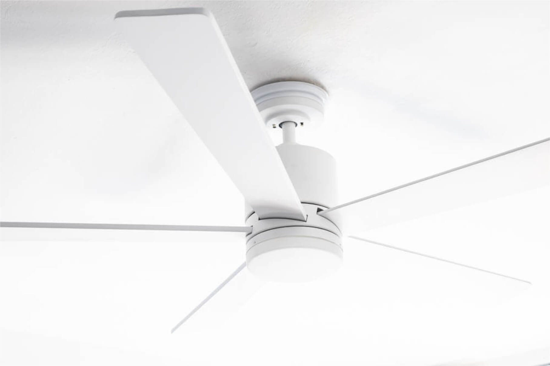 Weißer Deckenventilator mit fünf Flügeln vor einer weißen Decke.