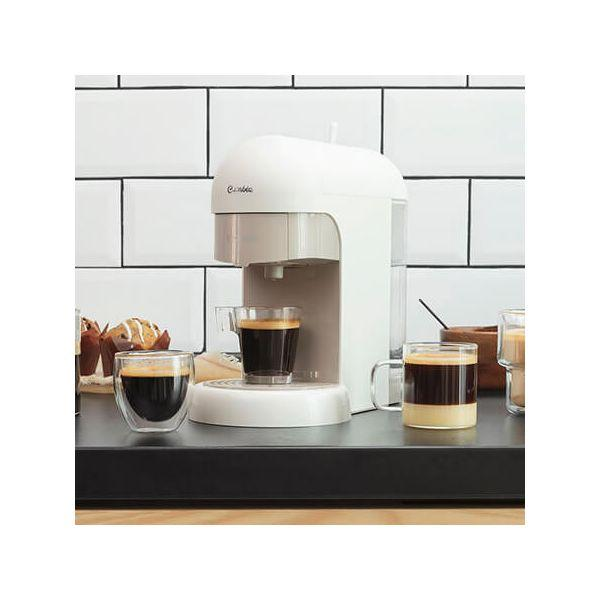 Eine weiße Espressomaschine mit zwei Kaffeegläsern auf einer schwarzen Theke.