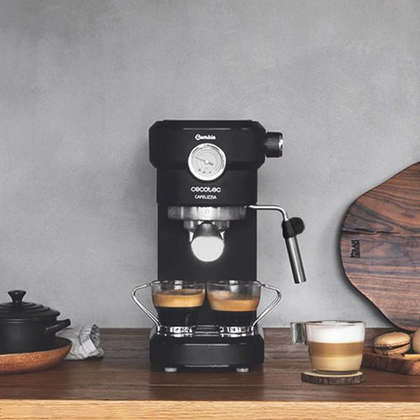 Eine schwarze Espressomaschine mit zwei Kaffeetassen und einem Holzbrett auf einem Holztisch.