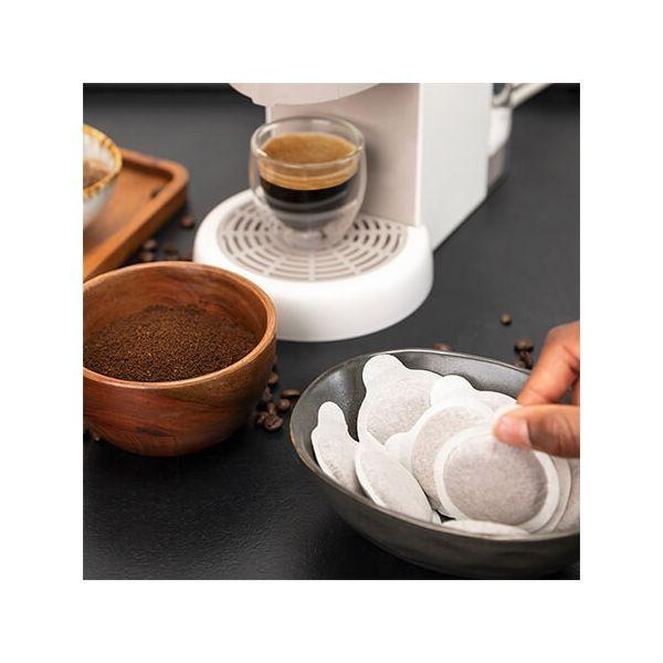 Kaffeemaschine mit Espresso. Kaffeepulver in einer Holzschale. Kaffeepads in einer Schale.