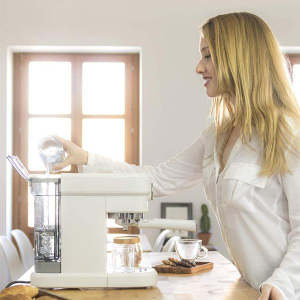 Donna che versa acqua in una macchina da caffè bianca.