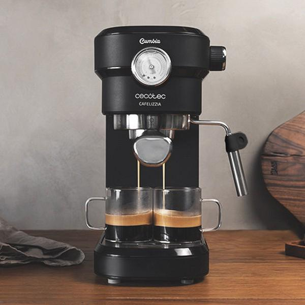 Eine schwarze Espressomaschine mit zwei klaren Glasbechern, die mit Kaffee gefüllt sind. Beiger Hintergrund.