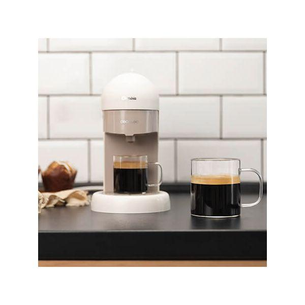 Kaffeemaschine mit zwei Gläsern gefüllt mit Kaffee und einem Muffin. Creme- und Beigetöne.