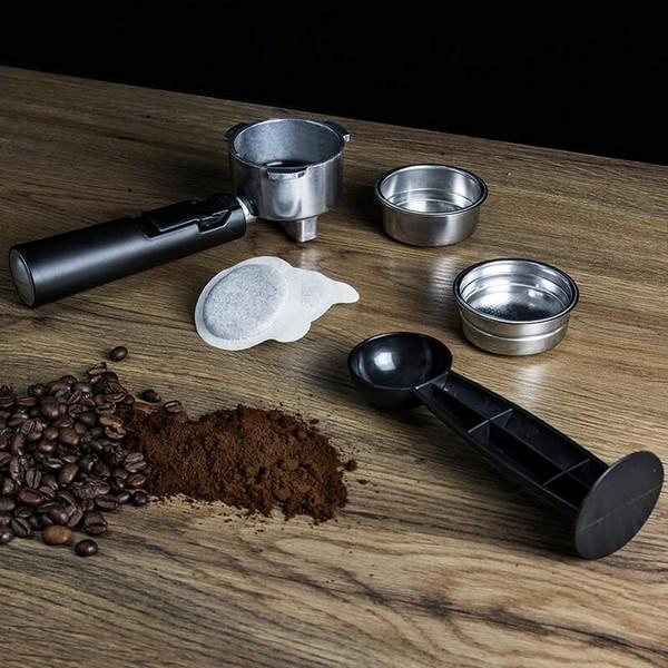 Kaffeezubereitung: Siebträger, Kaffeepulver, Bohnen, Filterpads und Zubehör auf Holztisch.