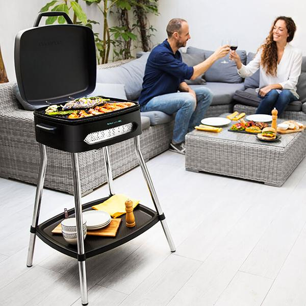 Una parrilla negra en un soporte con una pareja brindando con copas de vino.