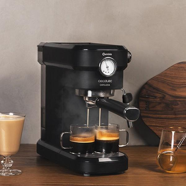Schwarze Espressomaschine, die Kaffee zubereitet. Zwei Gläser, eines mit Kaffee, das andere mit gelber Flüssigkeit.