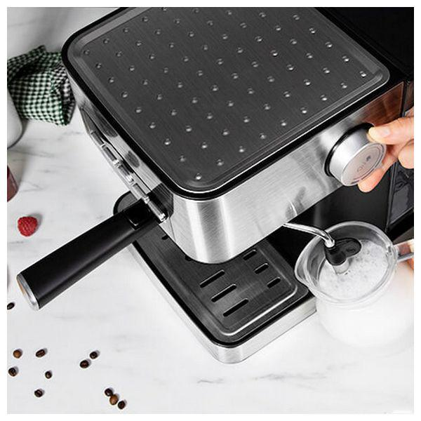 Macchina per espresso con manico, una tazza e una persona che gira un bottone.