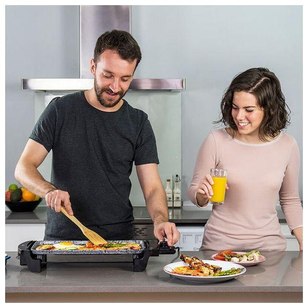 Mężczyzna i kobieta gotują jajka na grillu. Stoją w kuchni z jedzeniem i sprzętem.