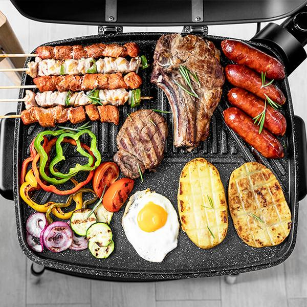 Parrilla con comida a la parrilla: bistec, salchichas, verduras y huevos.