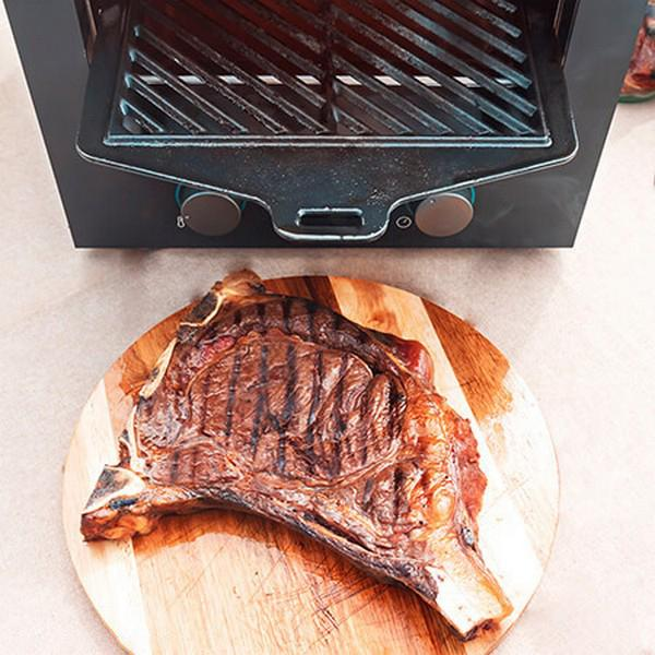 Gegrilde biefstuk op houten snijplank, onder een grill geplaatst, klaar om te koken.