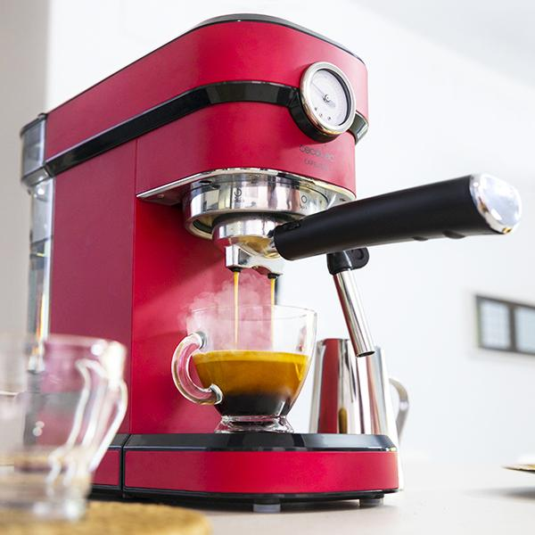 Rote Espressomaschine mit einer Glas-Tasse, die sich mit Kaffee füllt. Eine silberne Anzeige ist sichtbar.