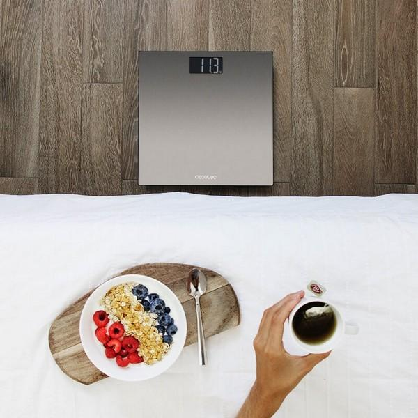 Srebrna waga na drewnie. Miska owoców i herbata na łóżku, ręka trzymająca filiżankę.