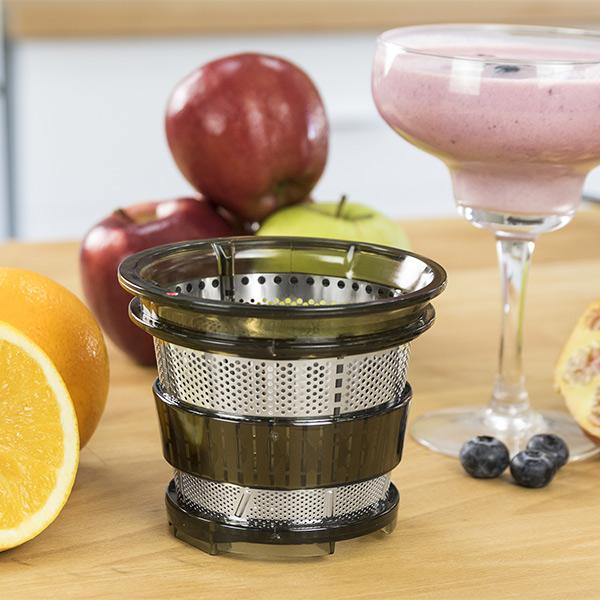 Partes de exprimidor con manzanas, naranjas y un batido. Primer plano sobre una superficie de madera.