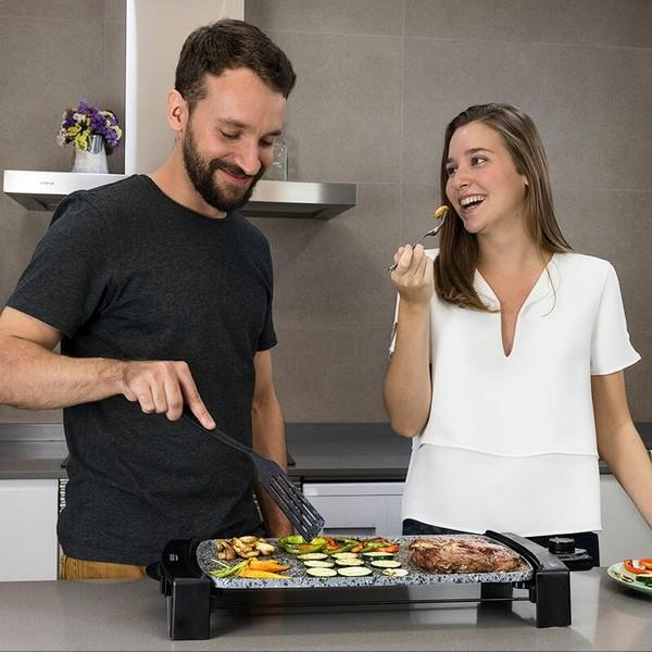 Para gotująca na grillu, uśmiechnięta. Różne potrawy na grillu.