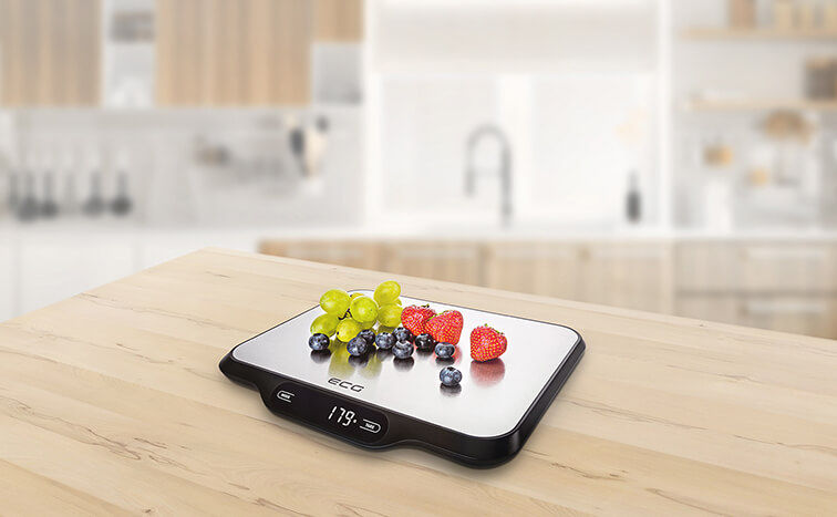 Waga kuchenna z winogronami, jagodami i truskawkami na drewnianym stole.