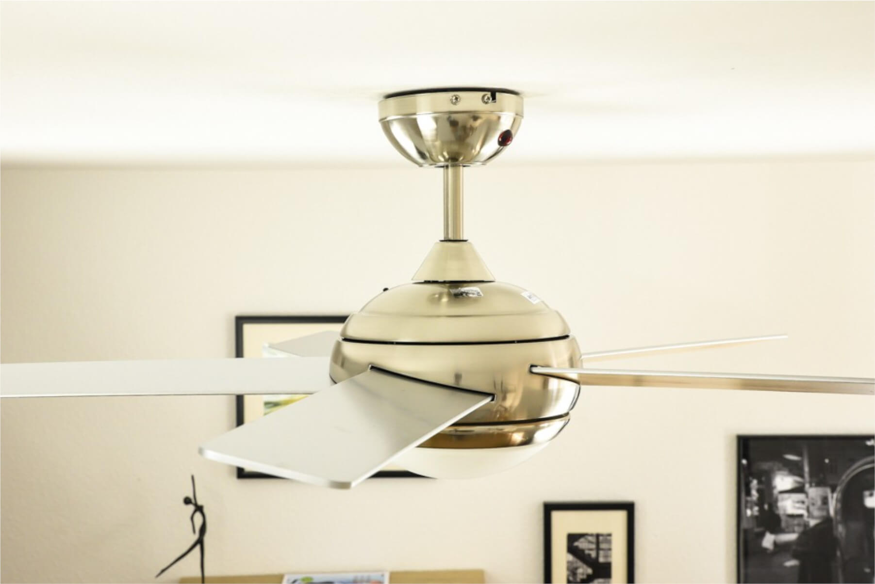 Deckenventilator mit weißen Flügeln, silbernem Motorgehäuse, in einem Raum.