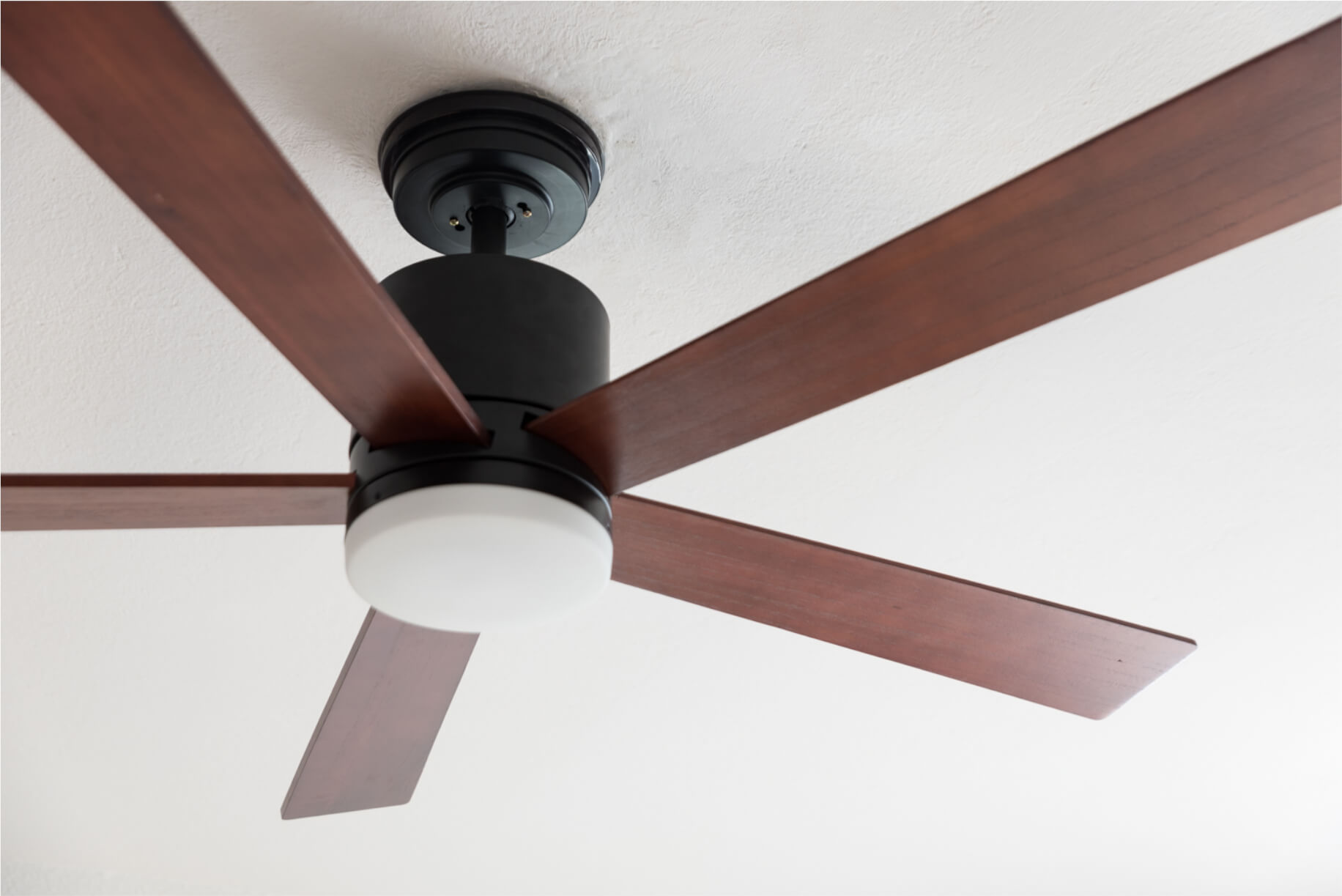 Deckenventilator mit braunen Flügeln und schwarzem Motor.