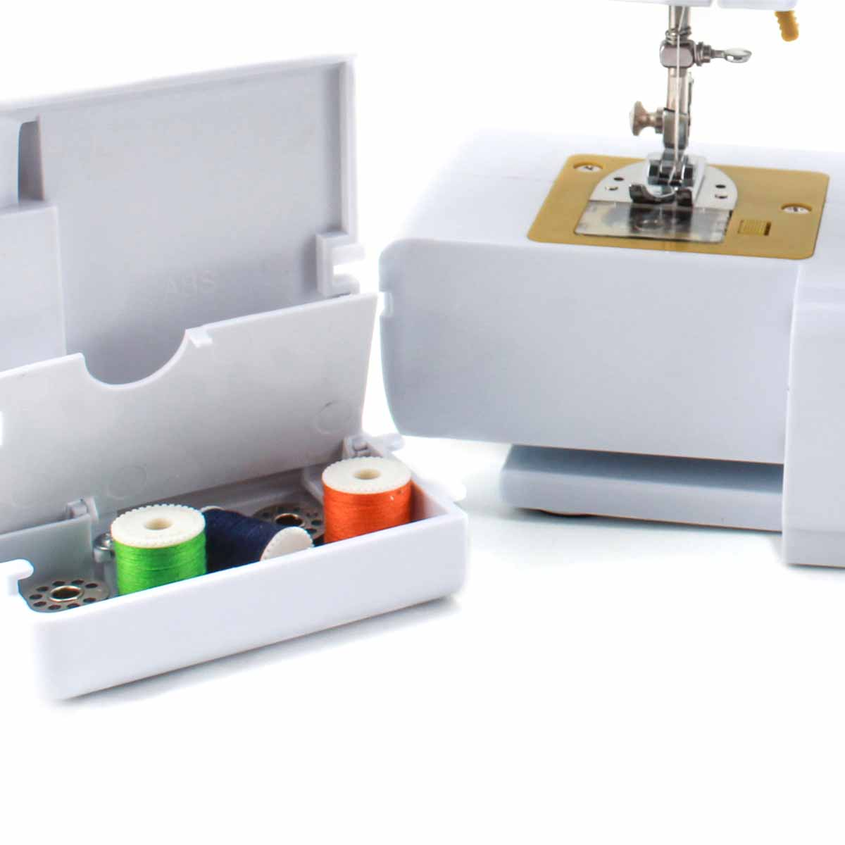 Maszyna do szycia z otwartym pudełkiem na nici. Maszyna jest biała i ma złotą płytkę.