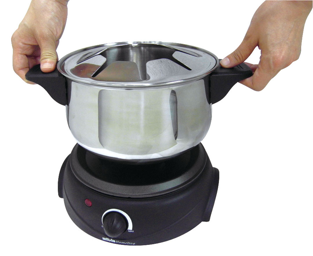 Mani che tengono una pentola per fonduta argentata su una base elettrica nera. Sfondo bianco.