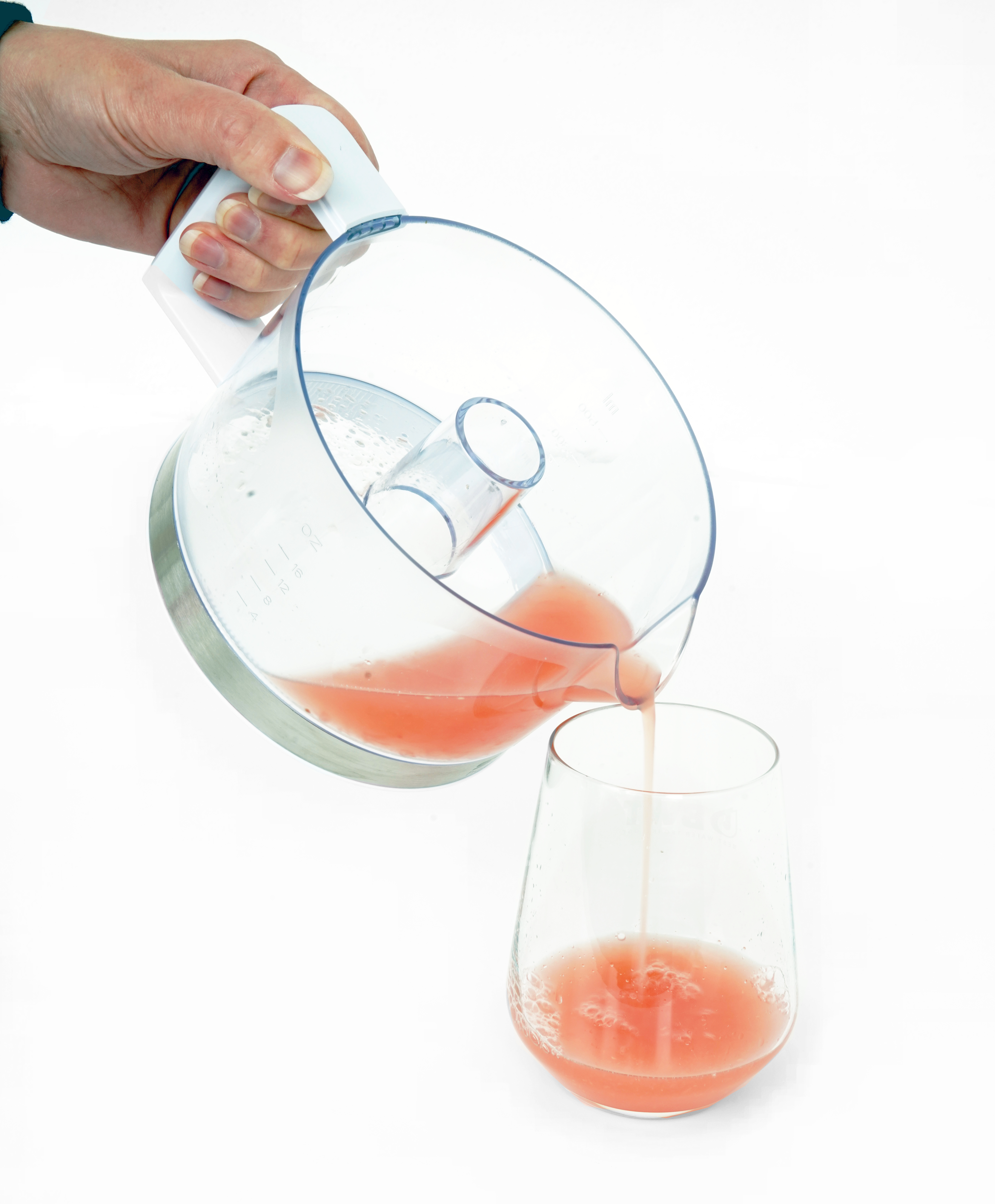 Saft wird aus einem transparenten Behälter in ein Glas gegossen. Weißer Hintergrund.