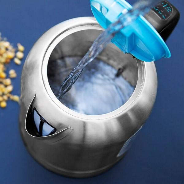Zilveren waterkoker met water dat uit een blauw deksel wordt gegoten, op een blauwe achtergrond.