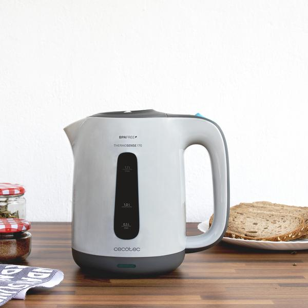 Bollitore elettrico bianco con manico nero e grigio. È su un tavolo di legno.