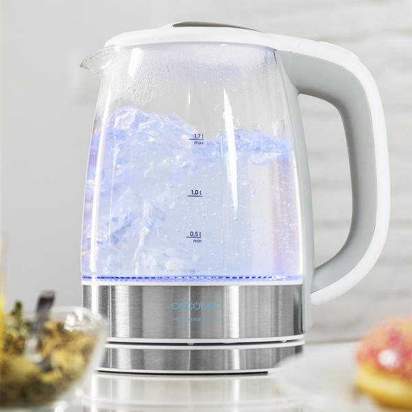 Elektrischer Glaskessel mit kochendem Wasser. Blaues Licht beleuchtet das Wasser. Weißer und grauer Griff.